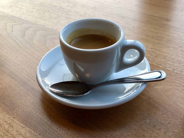 Cup with saucer and spoon, containing espresso